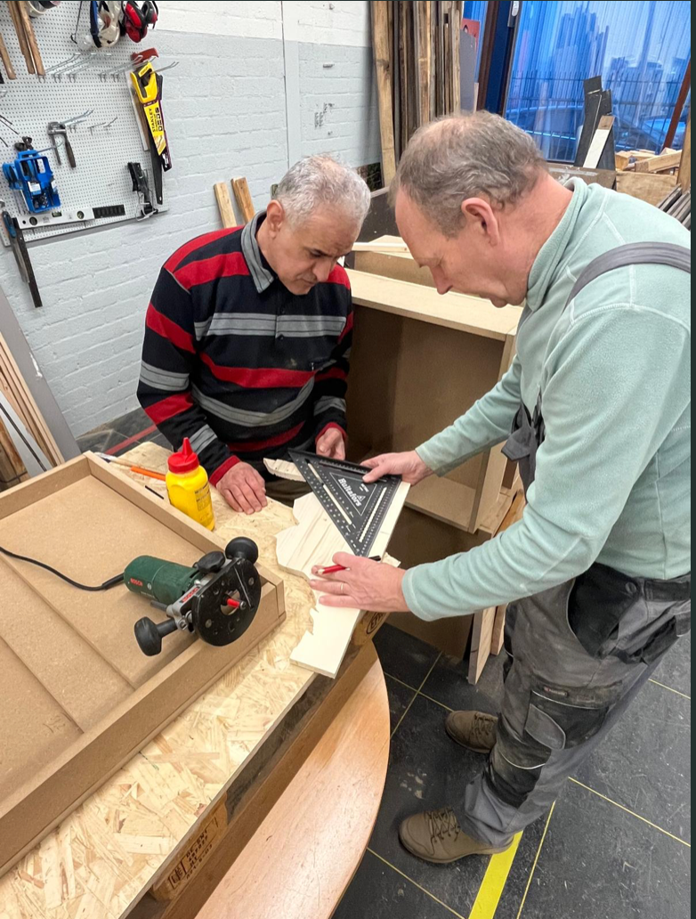 Samen werken aan een houten object in de sociale houtwerkplaats