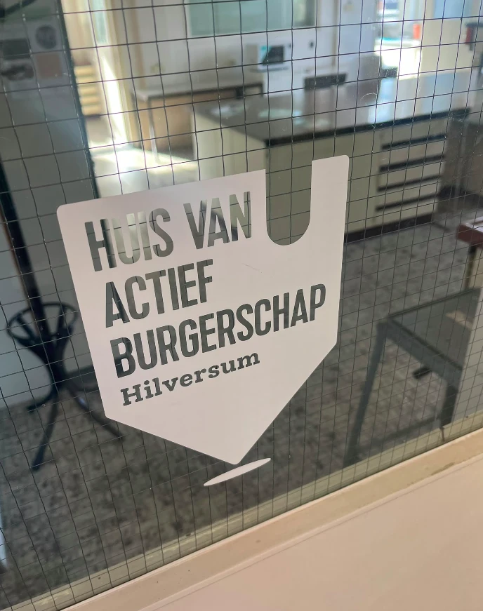 Het teken van het Huis van Actief Burgerschap Hilversum op de glazen deur